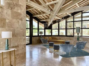 A modern interior with a high ceiling, large windows, and a seating area with a sofa and chairs. - Domaine de la Reynaude (Aurons)