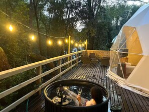 A hot tub on a wooden deck with a tent in the background.