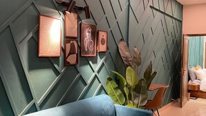 A modern interior with a blue sofa, a wooden coffee table, and a wall with geometric patterns and framed artwork. - Lovely 1-bedroom apartment with AC in vibrant Karachi (Karachi)