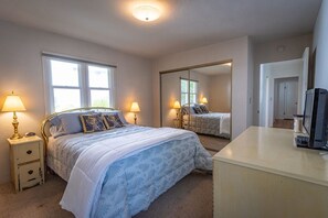 A bedroom with a bed, bedside lamps, a desk with a computer, a mirror, and a window. - 10-Min Walk to Downtown & Lake • 10-Min Drive to Schweitzer Base (Sandpoint)
