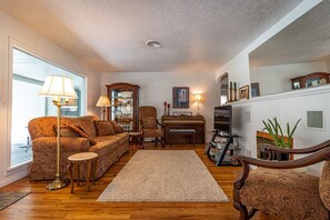 A living room with a sofa, armchairs, a piano, a mirror, and a bookshelf. - 10-Min Walk to Downtown & Lake • 10-Min Drive to Schweitzer Base (Sandpoint)