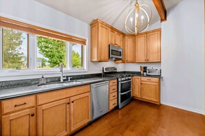 Una cocina con armarios de madera, un lavamanos de acero inoxidable, un microondas, una estufa y un tostador.
