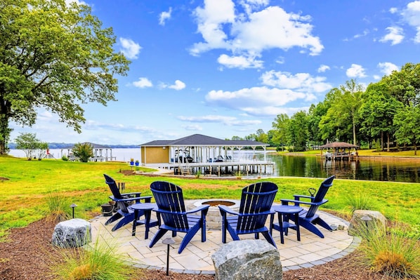 A lakeside patio with outdoor seating and a dock extending into the water.