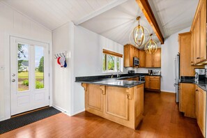 A kitchen with wooden cabinets, a central island, and pendant lighting.