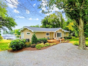 A two-story house with a front porch, a covered deck, and a view of a lake.