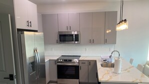 Una cocina moderna con electrodomésticos de acero inoxidable, microondas, estufa y fregadero.