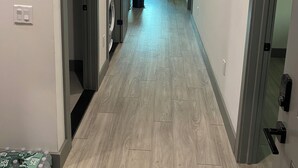 Un pasillo con piso de madera clara, una ventana con vistas y una puerta que da a un área de lavandería.