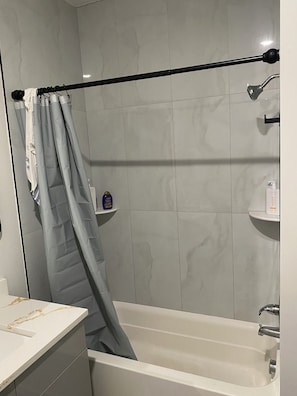 A bathroom with a bathtub, a shower curtain, and a towel rack.