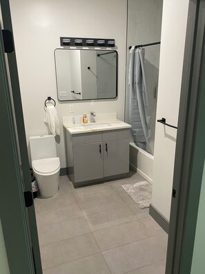 Een badkamer met toilet, wastafel, spiegel en douche.