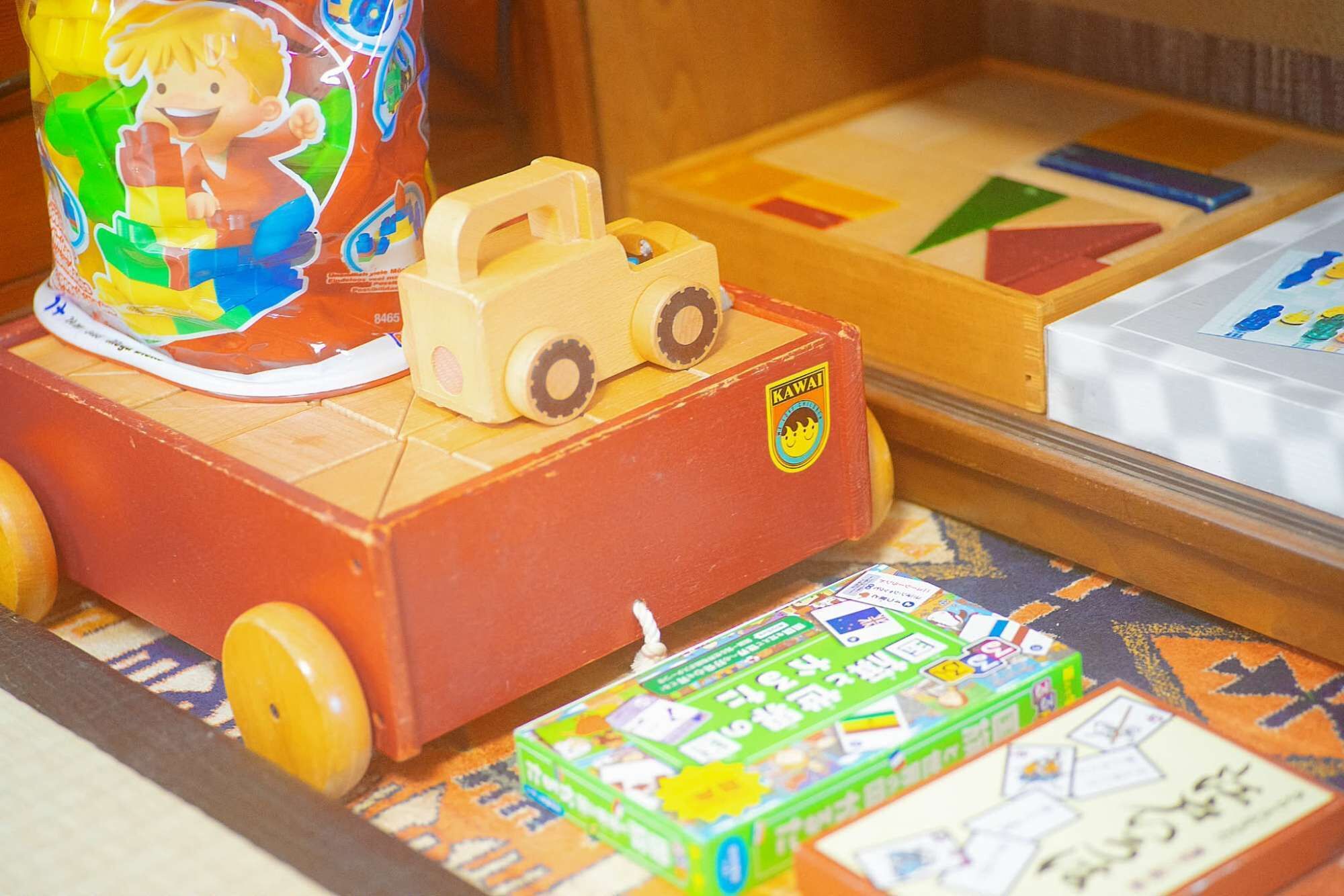 A wooden toy truck with a sticker on it, placed on a table with various board games.