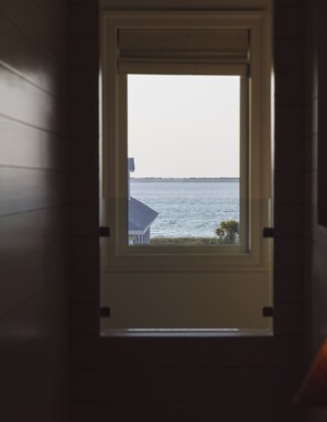 Ein Fenster mit Blick auf ein Gewässer und eine entfernte Küstenlinie.