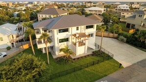 A two-story house with a covered patio and a view of the ocean. - New Stunning Luxury Beach Home with Private Pool! (Pensacola Beach)
