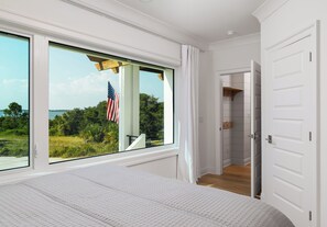 Un dormitorio con una ventana grande, una bandera estadounidense y vistas a zonas verdes.