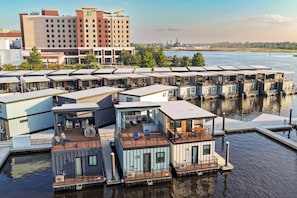 A waterfront property with floating homes, a marina, and a distant building. - Sol at The Cove Riverwalk Villas (Wilmington)