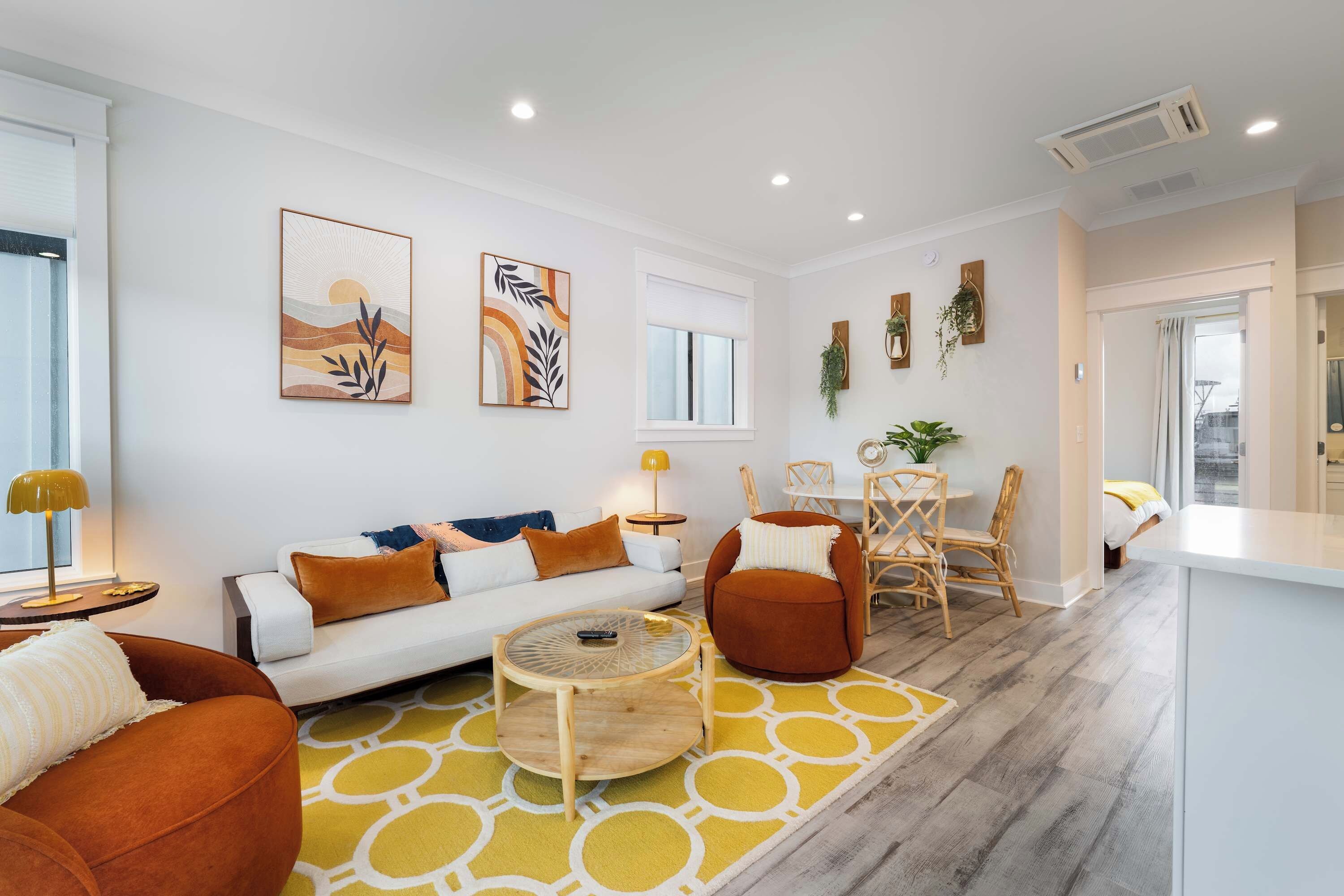 A modern living room with a sofa, armchairs, a coffee table, and a dining area with a table and chairs.