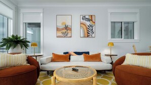 Una sala de estar moderna con un sofá, dos sillones, una mesita de centro y obras de arte en las paredes.