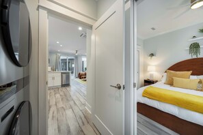 Habitación de hotel con cama, mesita de noche, lámpara y vistas a la cocina y la sala de estar.