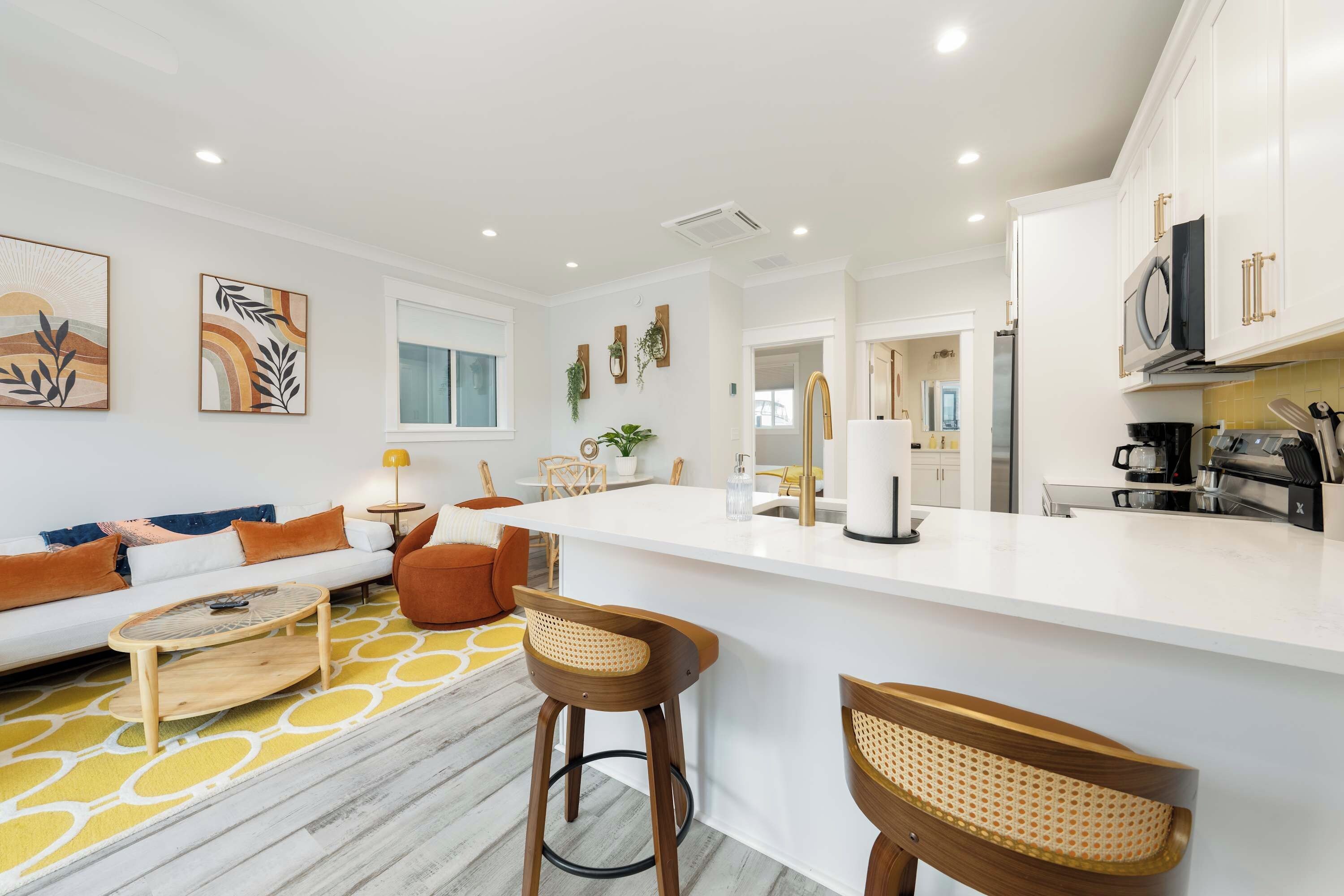 A modern kitchen with white cabinets, a central island, and bar stools.