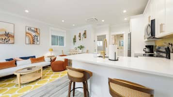 A modern kitchen with white cabinets, a central island, and bar stools.