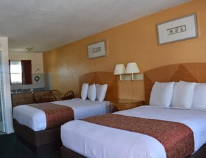 Ein Hotelzimmer mit zwei Betten, einer kleinen Küchenzeile und einem Badezimmer.