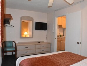 Ein Schlafzimmer mit einem Bett, einem Schminktisch, einem Fernseher und einem Spiegel.