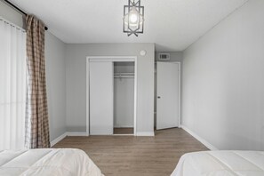 Un dormitorio con dos camas, un armario y una ventana con cortinas.