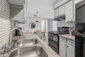 Eine moderne Küche mit Edelstahlgeräten, einer Arbeitsplatte aus Granit und einem Essbereich mit Tisch und Stühlen.