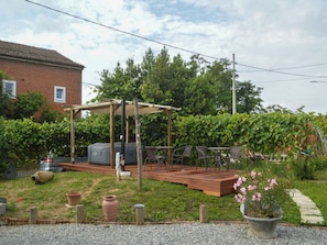 Ein Garten mit einer Holzterrasse, Gartenmöbeln und einer Pergola.