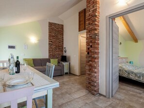 Ein kompakter Wohnraum mit Essbereich, einer Couch, einem Fernseher und einem Bett.