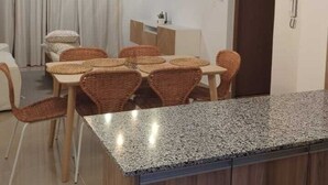 Una cucina moderna con un piano di lavoro in granito, mobili in legno e un'area pranzo con sedie in vimini.
