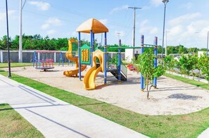 Ein Spielplatz mit Rutsche, Klettergerüsten und Schaukeln.