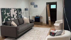 A modern living room with a grey sofa, a white armchair, a coffee table, and a floor lamp.