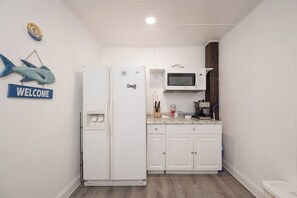 A compact kitchen with a white refrigerator, a microwave, and a coffee machine.