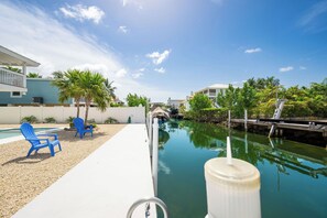 A swimming pool with a narrow waterway, a blue chair, and a white structure.
