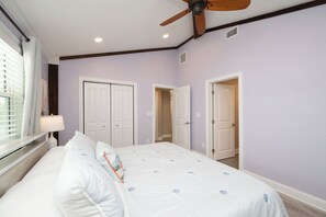 A bedroom with a bed, a ceiling fan, and two doors.