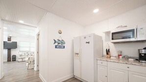 Uma cozinha moderna com armários brancos, um micro-ondas Samsung e uma geladeira.