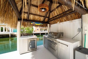 Un espace cuisine extérieur équipé d’un barbecue, d’un réfrigérateur et offrant une vue sur un plan d’eau.