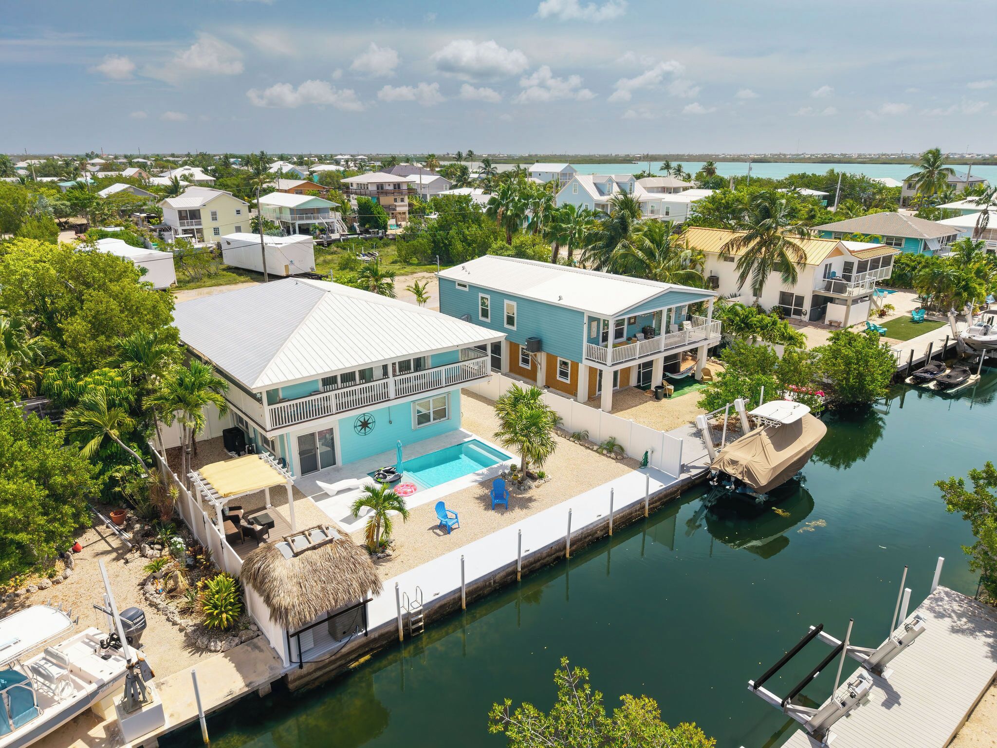 A two-story house with a pool, dock, and marina.