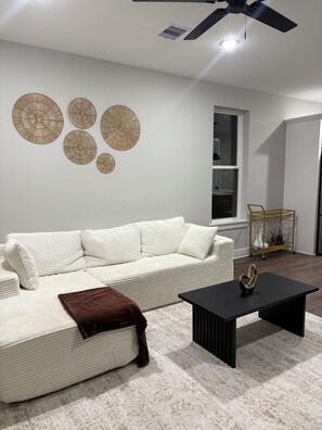 Ein Wohnzimmer mit weißem Sofa, einem schwarzen Couchtisch und Wanddekoration.