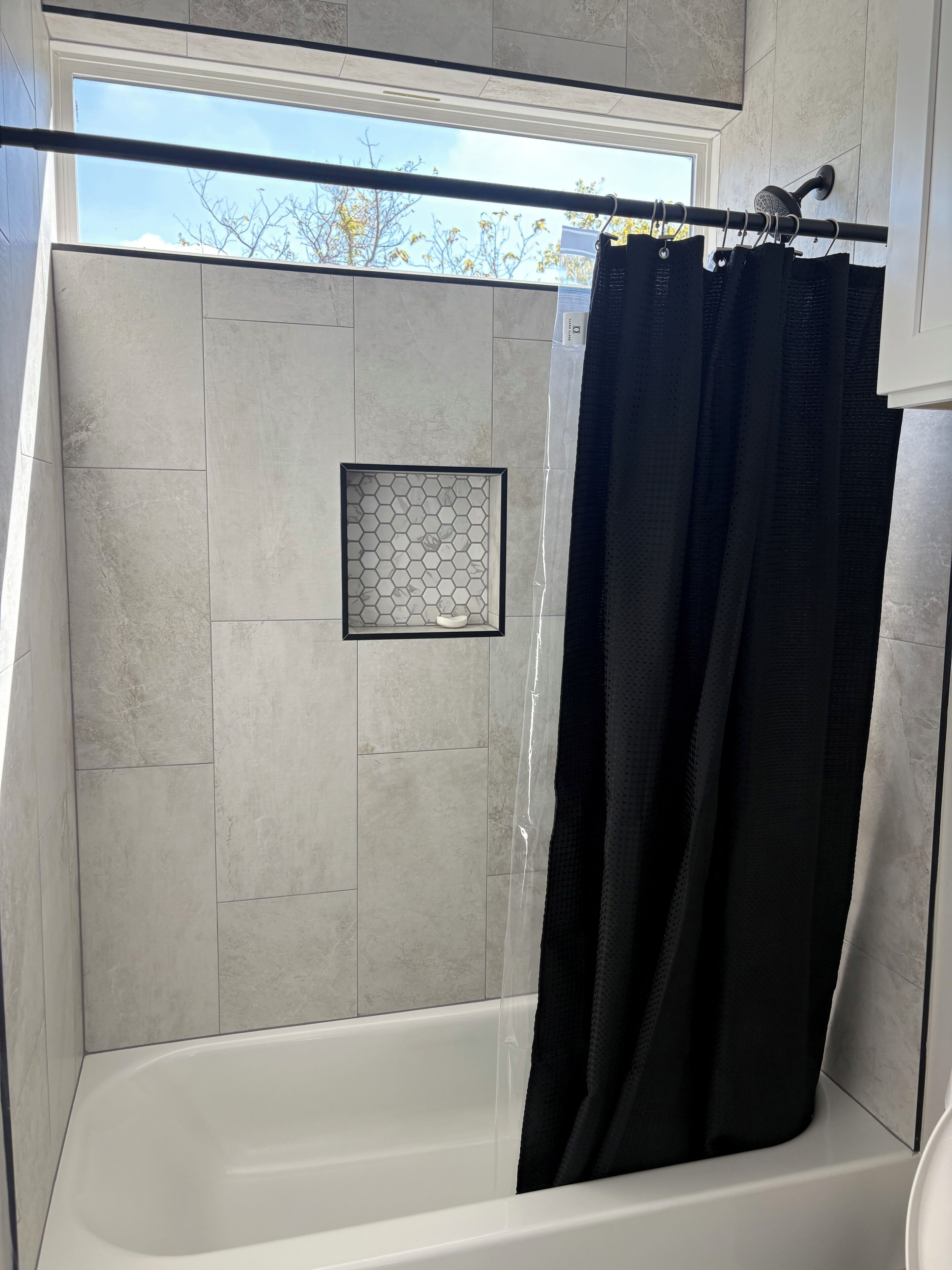 Ein Badezimmer mit Badewanne, Duschbereich und Fenster.