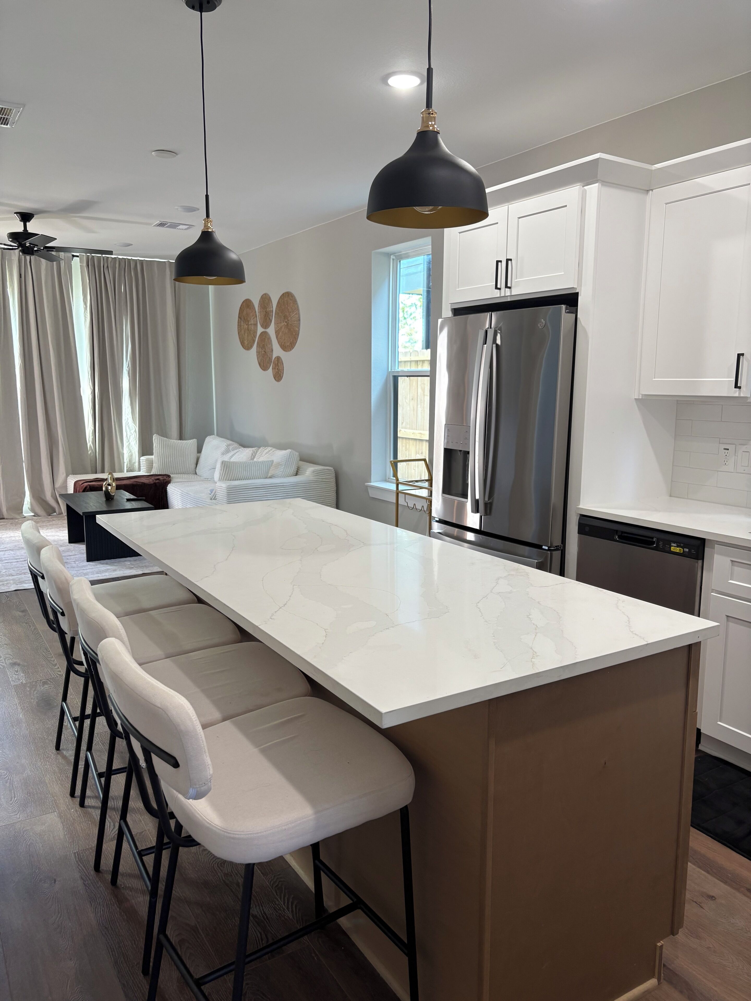 A modern kitchen with a large island, stainless steel appliances, and pendant lighting.