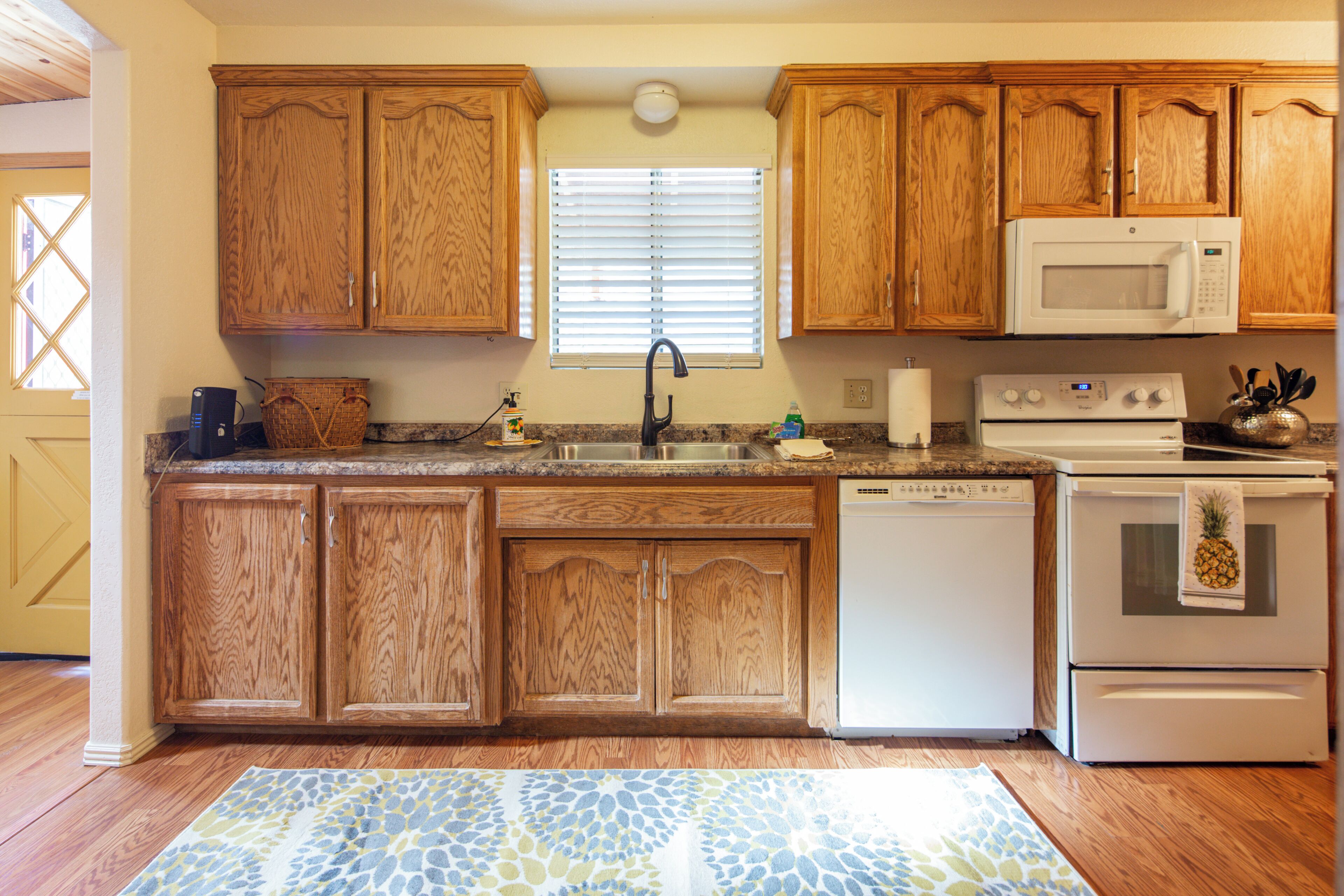 A kitchen with wooden cabinets, a microwave, a dishwasher, and a stove.