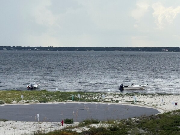 En lugn sjö med båtar, en sandstrand och en väg som leder till en parkeringsplats.