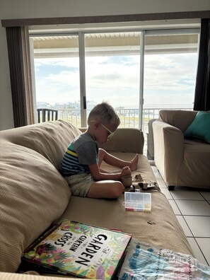 A child sitting on a sofa with a book titled 'Garden' and a toy. - 3-bedroom condo in Navarre Beach with Golfcart (Navarre)