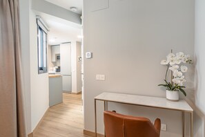 Een modern interieur met een houten vloer, een witte console tafel, een bruine lederen stoel en witte orchideeën.