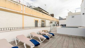 Een terras op het dak met lounge fauteuils, een tafeltje en een zwembad.