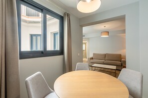 A modern room with a round table, two chairs, a sofa, and a window with curtains. - B2 Apartment with Cathedral Views – City Center & Pool (Seville)