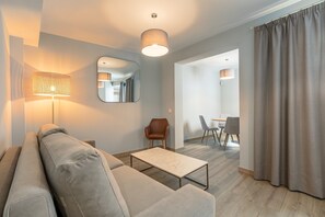 Ein stilvolles Wohnzimmer mit Sofa, Couchtisch, Lampe, Spiegel und Blick in den Essbereich.