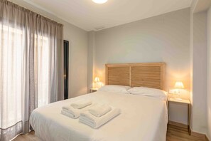 Een hotelkamer met een groot bed, twee bedlampen en een raam met gordijnen.