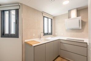 Eine moderne Küche mit integriertem Spülbecken, einer Holz-Schneidebrett und einem Fenster mit Jalousien.